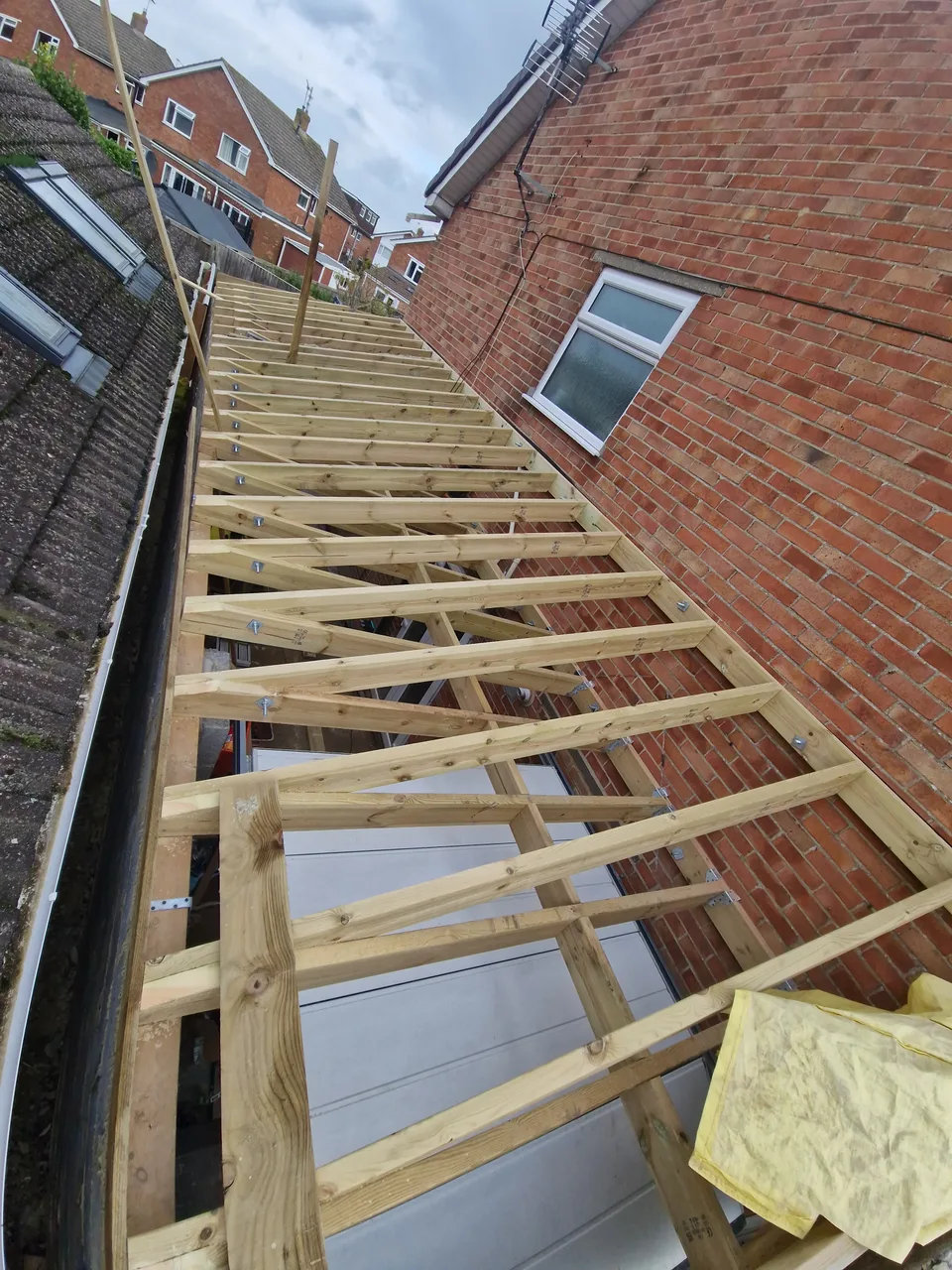 Timber roof framing beside an existing brick wall
