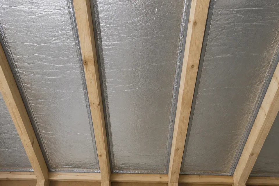 AI illustration of fully seated foil-faced insulation boards with continuous compressible edge seals between rafters